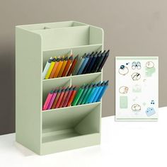 an office desk with a pen holder and colored pencils in front of the box