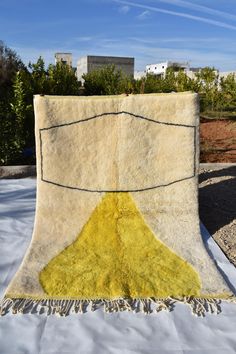 a yellow and white area rug on top of a bed in the middle of a field