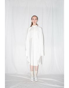 White zero waste cloak shirt is bias-cut that ensures a voluminous silhouette and flattering fit. Constructed from 100% Italian cotton, the shirt features slim cut collar, front covered placket button closure, 2 patch pockets, buttoned side seam vents and elongated one button sleeve cuffs.FEATURES:- Cloak shirt- 100% Italian cotton- Zero waste product- Side seam slits with buttons- Slim collar- Concealed front placket button closure- Bias cut- Styled here with our White Artisanal Shoes- Entirely Spring Long Sleeve Shirt With Concealed Placket, Oversized Fall Top With Concealed Placket, Oversized Top With Concealed Placket For Fall, Spring Shirt With Concealed Placket And Shirttail Hem, White Blouse With Concealed Placket For Spring, Oversized White Shirt Dress For Fall, White Shirt With Fold Down Collar For Fall, Modern Fall Shirt For Daywear, Fall Daywear Tops With Concealed Placket