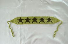 a crocheted object with stars on it laying on a white sheet in the shape of an arrow