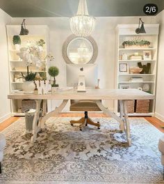 a room with a rug, chair and table in it that has a chandelier hanging from the ceiling