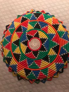 a multicolored basket sitting on top of a bed