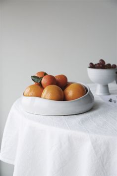 a white bowl filled with oranges on top of a table