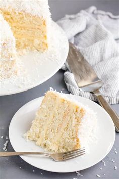 a slice of coconut cake on two plates with a fork next to the rest of the cake