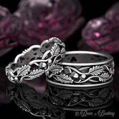 two wedding rings sitting next to each other on top of a black surface with pink flowers