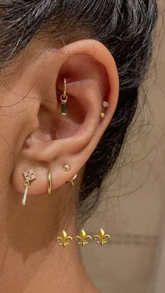 a woman wearing gold ear piercings with four leaf designs on the front and back of her ear