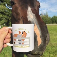 a person holding a coffee mug in front of a horse's face and nose