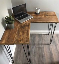 a laptop computer sitting on top of a wooden desk next to a potted plant