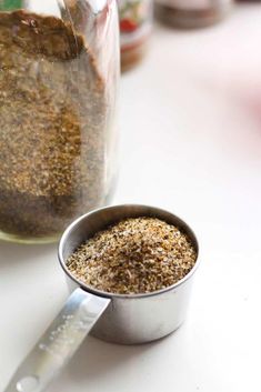 a jar filled with spices next to a measuring spoon