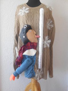 a knitted sweater hanging on the wall next to a stuffed animal wearing a hat and scarf