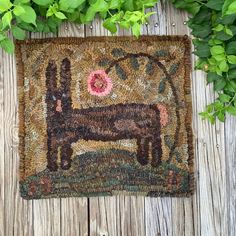 a dog hooked up to a door mat on a wooden floor next to some plants