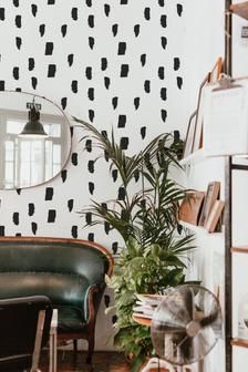 a living room with black and white wallpaper, green leather chair and potted plant