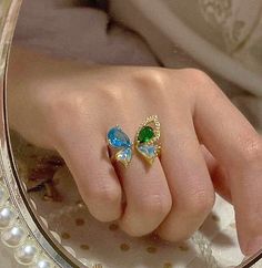 Super stunning butterfly statement cocktail ring, in gorgeous blue and green aquamarine color. Butterfly wings design, looks luxurious and sparkle. Open adjustable ring, easy to adjust for US size 4-10 easily. This ring is one of the kind, give you exquisite dainty vibes effortlessly! 💎 Features: ♥ Material: gold plated copper, enamel ♥ Main stone: blue and green zircon ♥ Side Stone: cubic zirconia ♥ Open and adjustable 💎 Details: ♥ Approximate Measurements : 24mm diameter ♥ Weight: 5g ♥ Nicke Butterfly Wings Design, Wedding Ring Cuts, Girly Rings, Flying Butterfly, Aquamarine Color, Green Aquamarine, Color Butterfly, Lace Ring, Buy Earrings