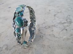 From Porans collection: Sterling Silver Bracelet with 28 stones inlaid. Turquoise, Labradorite, Green quartz, opalite & Aventurine. The bracelet can be ordered with a combination of stones. Please check with me what options are available Dimensions: Max Width: 20 mm bangle size- 63 mm Please let me know if you have any questions. our jewelry shop on Etsy: http://www.etsy.com/shop/Porans Thank you for visiting our shop. Please visit my shop policies for additional information Unique Cabochon Bangle Bracelets, Green Bangle Bracelets In Fusion Style, Fusion Green Bangle Bracelets, Green Fusion Bangle Bracelet, Green Fusion Style Bangle Bracelets, Green Bangle With Natural Stones For Gift, Green Multi-stone Bangle Jewelry, Spiritual Green Bangle Cuff Bracelet, Handmade Green Sterling Silver Bangle