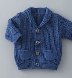 a blue knitted sweater with buttons on the front and back, sitting on top of a white surface