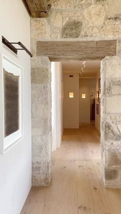 an open door leading to a hallway with stone walls and wood flooring on both sides