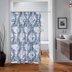 a blue and white shower curtain in a bathroom next to a sink on a wooden floor