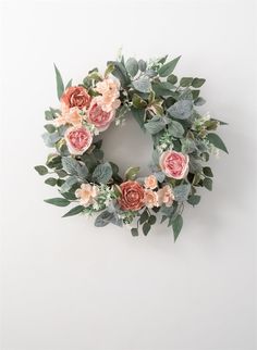 a wreath with flowers and greenery hanging on the wall