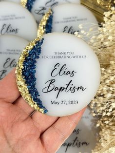 a hand holding some white and blue marbles with gold glitter on them that say, thank you for celebrating with us