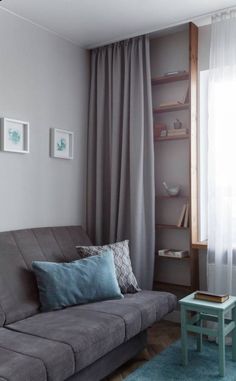 a living room with a gray couch and blue rug on the floor next to a window