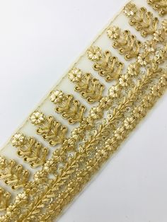 a gold foiled decorative ribbon with leaves and flowers on the side, set against a white background