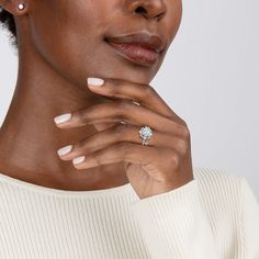 a woman wearing a white sweater and diamond ring