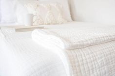 a bed with white sheets and pillows on top of it, next to a nightstand