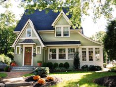 a green house with white trim and blue roof