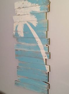 a wooden wall hanging with palm trees painted on it's sides and white paint