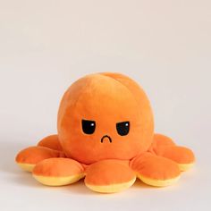 an orange stuffed animal with black eyes on it's face and arms, sitting in front of a white background