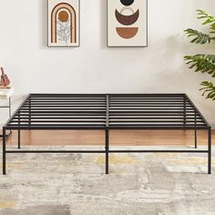 a metal bed frame sitting on top of a hard wood floor next to a plant