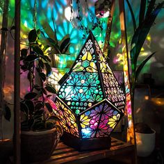 a colorful lamp sitting on top of a wooden shelf next to a potted plant