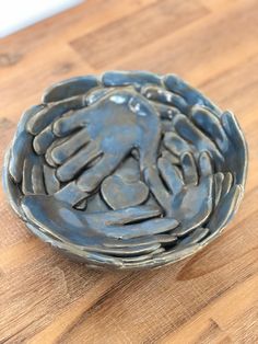 a bowl with two hands on it sitting on a wooden table