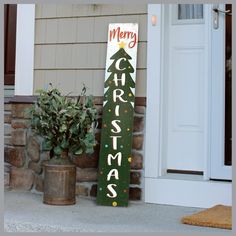 a merry christmas sign sitting on the side of a house next to a potted plant