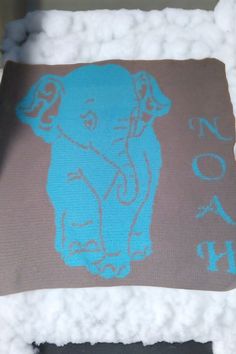 an elephant on a brown and blue towel with the word noah painted on it's side