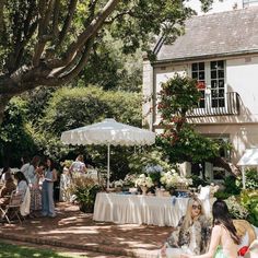 people are sitting at tables outside under umbrellas in the shade on a sunny day