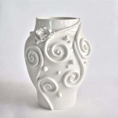 a white vase with swirly designs on the outside and inside, sitting against a white background