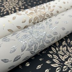 three rolls of fabric with gold and silver designs on them