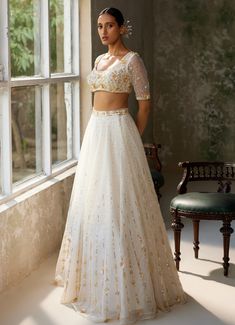 Embrace timeless elegance with the exquisite Ivory Embroidered Lehenga Set, crafted from pure silk organza. The full-length ivory lehenga showcases intricate hand-embroidery, adding a touch of opulence and tradition to the ensemble. Delicate motifs dance across the ethereal fabric, shimmering subtly in the light. Paired with matching half sleeved blouse features meticulous hand-embroidery, enhancing its luxurious appeal. A beautifully completed dupatta with hand-embroidered borders and motifs the ensemble's refined artistry. Perfect for a bride or bride to be Engagement or Roka or for intimate wedding ceremonies. Composition : Blouse - Soft Net, Lehenga & Dupatta - Pure Silk Organza Care: Dry Clean Only and Vacuum Storage This product can be customized for sleeves, blouse length and neckli Elegant Embroidered Cream Lehenga, Elegant Tissue Silk Lehenga With Gold Embroidery, Elegant Floor-length Choli With Gold Embroidery, Formal Organza Lehenga With Intricate Embroidery, Cream Organza Sets With Intricate Embroidery, White Embroidered Raw Silk Gown, Formal Lehenga With Gold Embroidery For Festivals, Cream Floor-length Sets With Intricate Embroidery, Elegant Organza Lehenga With Gold Embroidery