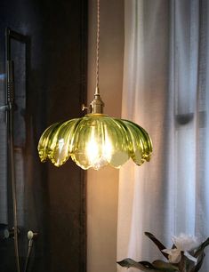 a green lamp hanging from a ceiling next to a window