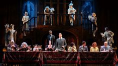 a group of people sitting on top of a table in front of a stage curtain