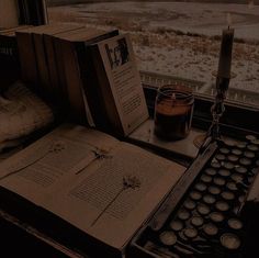 an open book sitting on top of a table next to a candle and some books