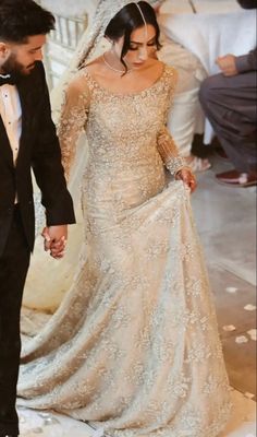 a bride and groom walking down the aisle at their wedding ceremony, dressed in an off - white gown