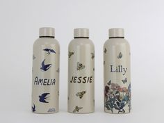 three personalized water bottles with birds and flowers on them, one is white and the other is blue