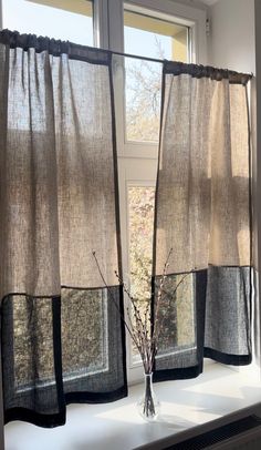 a vase filled with flowers sitting on top of a window sill next to two windows