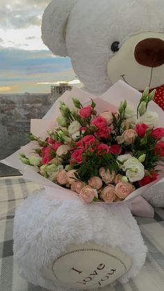 a white teddy bear sitting next to a bouquet of flowers