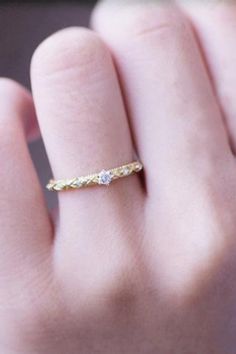 a woman's hand with a yellow gold ring on it and a diamond in the middle