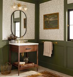 a bathroom with green walls and a white sink under a round mirror on the wall