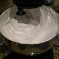 a large bowl filled with whipped cream sitting on top of a counter next to a blender