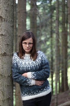 a woman standing next to a tree with her arms crossed in front of her face